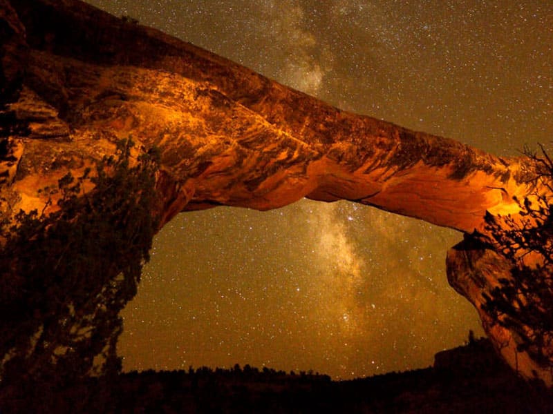 A rock arch at night with stars in the background