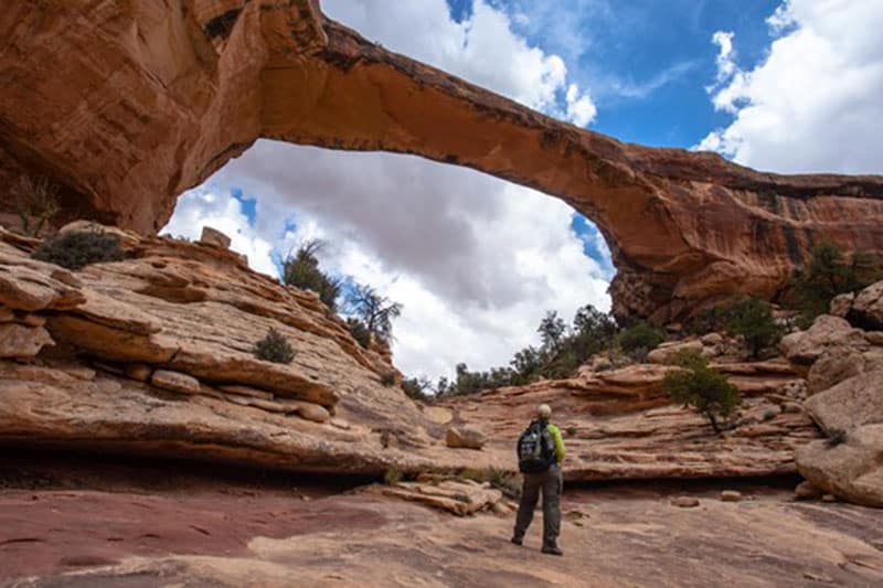 A hiker looking up at one of the natural bridges in Utah